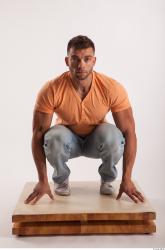 Kneeling pose orange thsirt light blue jeans of bodybuilder Harold
